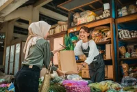 Pemilik UMKM melayani pelanggan yang kembali berbelanja di toko