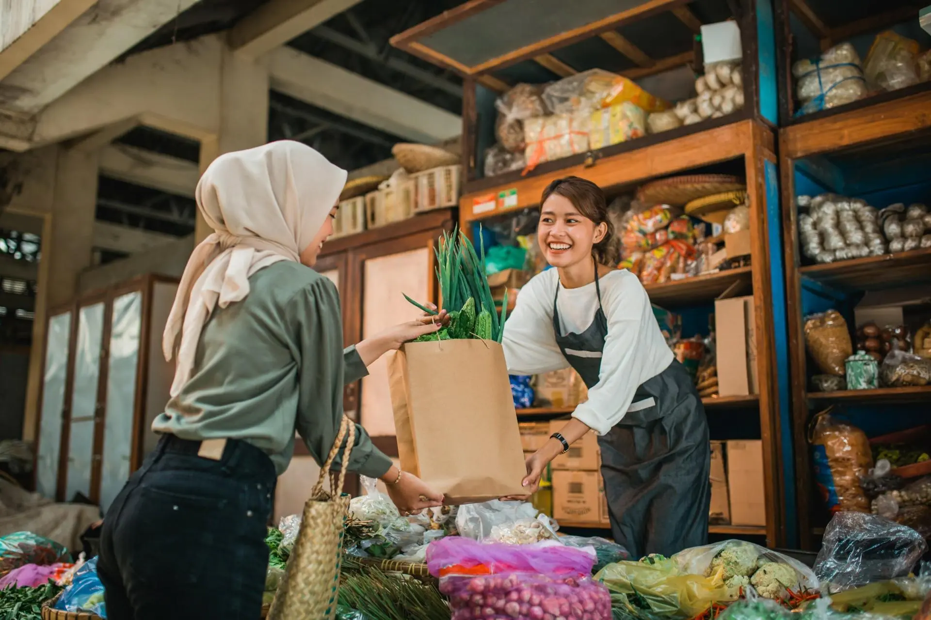 Pemilik UMKM melayani pelanggan yang kembali berbelanja di toko